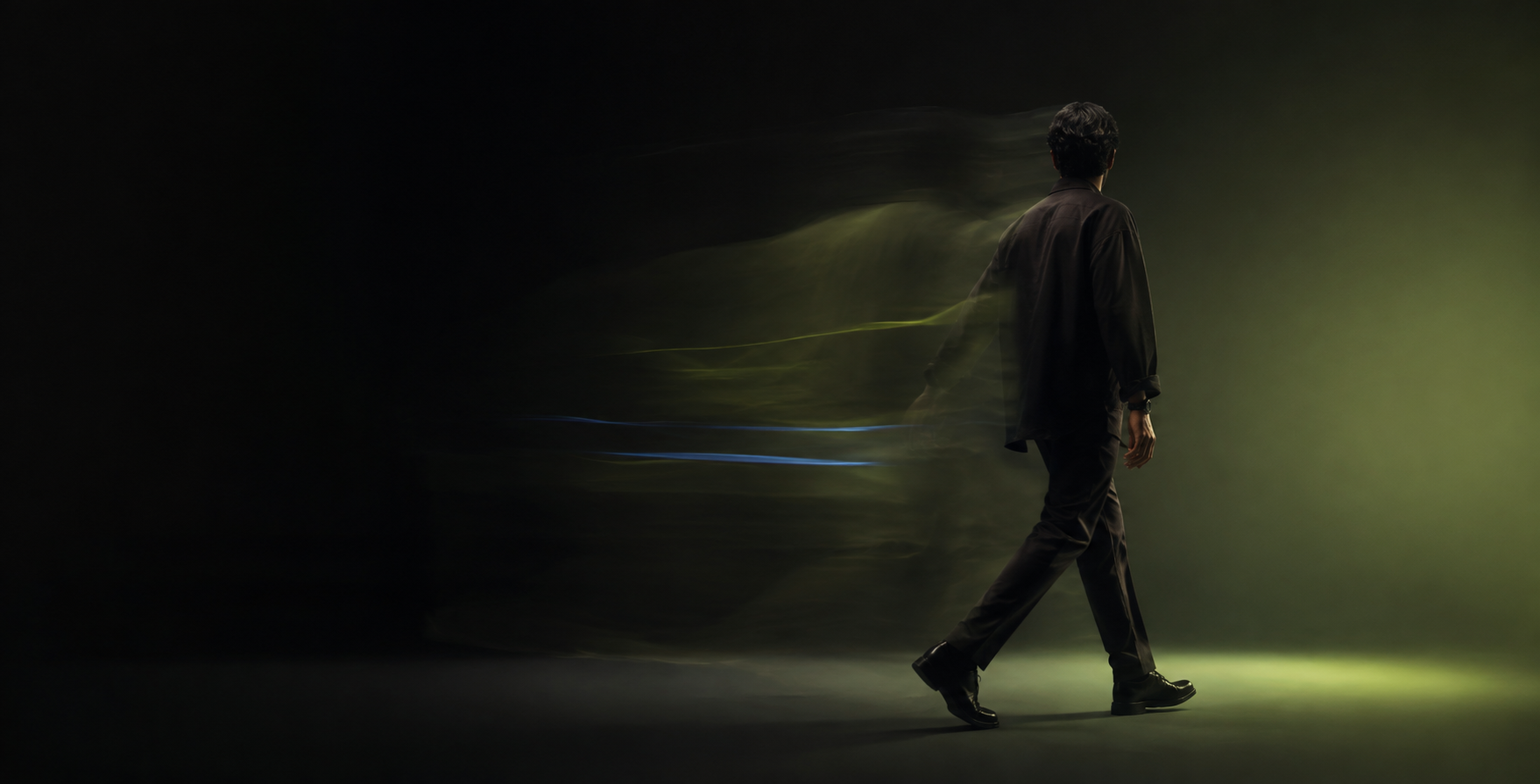 Conceptual editorial image of a creative professional walking through dark green light and subtle motion trails.